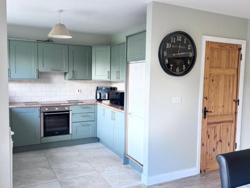 a kitchen with green cabinets and a clock on the wall at Clones Town House in Cluain Eois