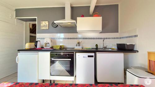 a small kitchen with white cabinets and a stove at Les Hirondelles in Ouroux