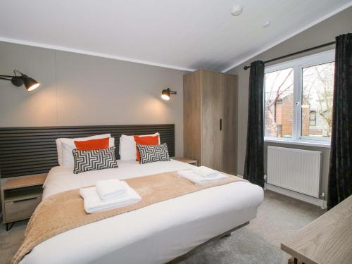 a bedroom with a large white bed with orange pillows at Tulip in Leominster