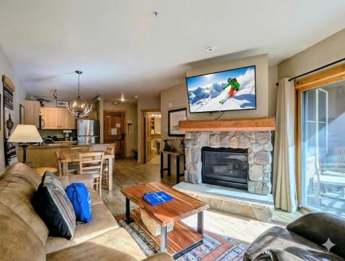 a living room with a fireplace with a tv above it at Buffalo Lodge 8320 by SummitCove Lodging in Keystone