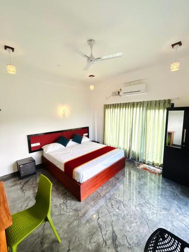 a bedroom with a large bed and a green chair at Flymount Homestay in Vagamon