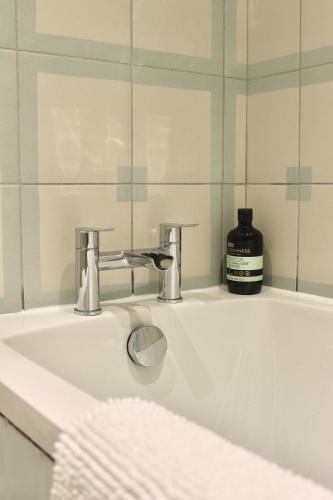 a bathroom sink with a mirror and a bottle of soap at Modern Country Cottage Stay in Lympsham