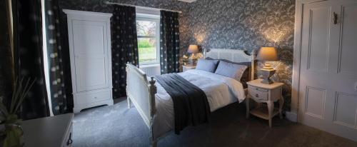 a bedroom with a bed and two lamps and a window at The Painted Cow in Beattock