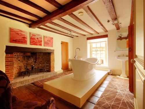 a living room with a bath tub and a fireplace at Sutherland House in Southwold