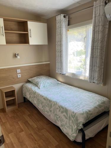 a small bedroom with a bed and a window at Mobil Home avec WIFI -6-8 Personnes in Lattes