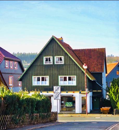 a green house with white windows on a street at Harz Flair Schierke in Schierke