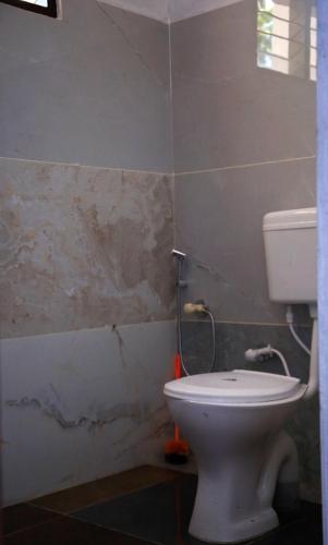 a bathroom with a white toilet in a room at Sree vinayaka homestay in Vagamon