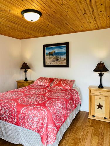 a bedroom with a red bed and two lamps at Snug Harbor Marina and Resort in Chincoteague