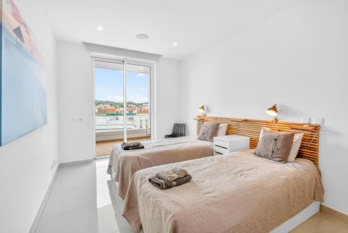 two beds in a white room with a window at Penthouse by the Marina in Lagos