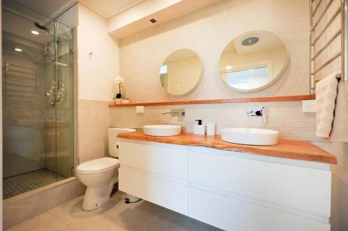 a bathroom with two sinks and a toilet and a shower at Luxury Beach View Escape in Melbourne