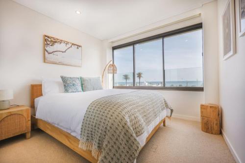 a bedroom with a bed and a large window at Luxury Beach View Escape in Melbourne