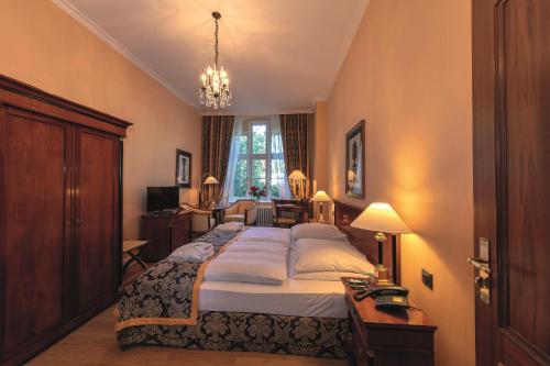 a bedroom with a large bed and a chandelier at Hotel Altes Gymnasium in Husum
