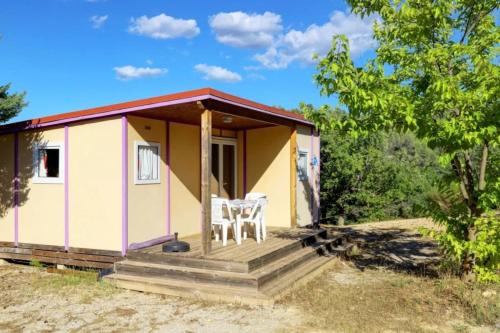 a small yellow and white house with a porch at Camping Verdon familial 3 étoiles - 20 min du lac de Sainte Croix in Esparron-de-Verdon
