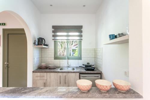 a kitchen with a sink and two stools at 3 Goddesses' studios in Koukounaries