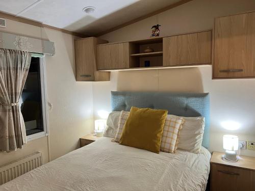 a bedroom with a bed with a yellow pillow on it at Rockley Valley TV36 in Lytchett Minster