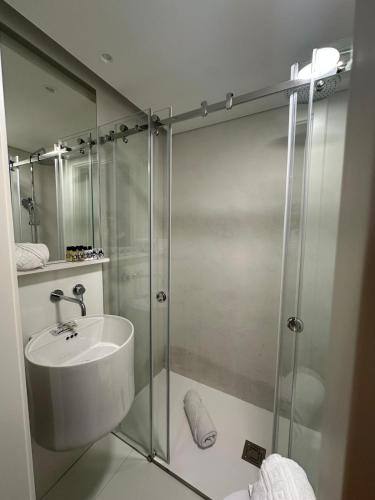 a bathroom with a glass shower with a sink at Rossio Garden Suites in Lisbon