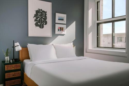 a white bed in a room with a window at The Alexander Hotel - Old Montreal in Montréal