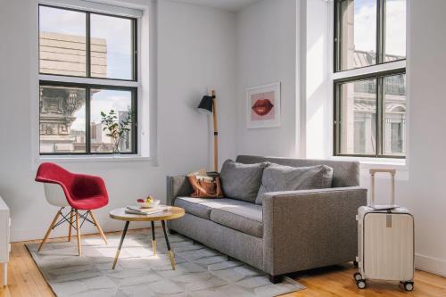 a living room with a gray couch and a red chair at The Alexander - Old Montreal in Montreal