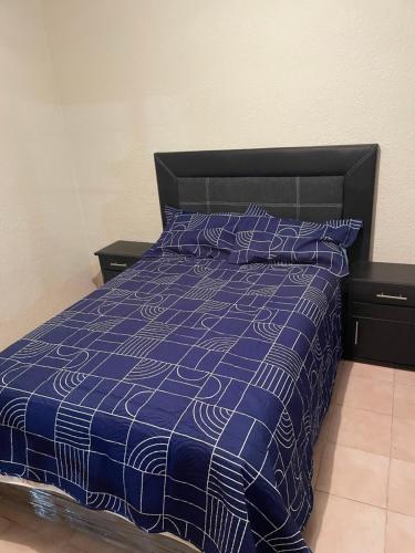 a bed with a blue and white comforter and pillows at Casa Fuentes in Zacatlán