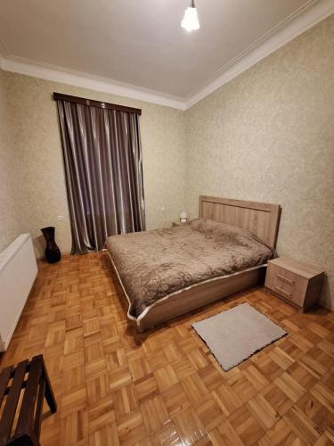 a bedroom with a bed and a wooden floor at Central Apartment Tskaltubo in Tsqaltubo