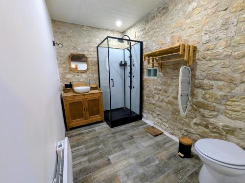 a bathroom with a glass shower and a toilet at Gîte Val de Loire Le Puits in Loudun