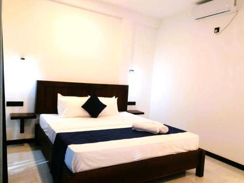 a bedroom with a bed with white and black sheets and pillows at The Vinza in Hikkaduwa