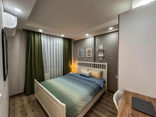 a bedroom with a bed with green curtains and a table at Smartly Designed Cozy 1BR Apartment in Antalya