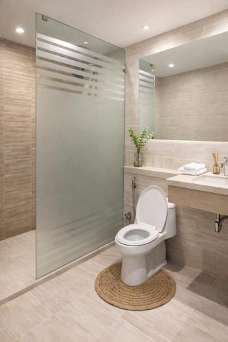 a bathroom with a toilet and a glass shower at The Nest Apartment in Rawalpindi