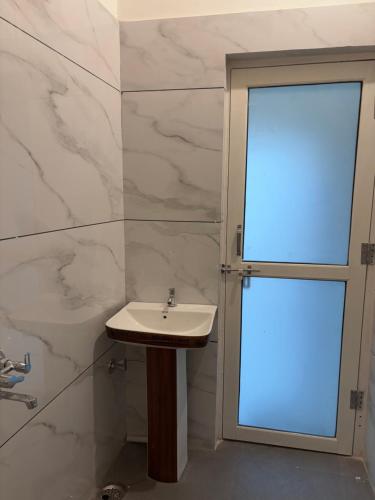 a bathroom with a sink and a glass door at Keshav Palace in Pushkar