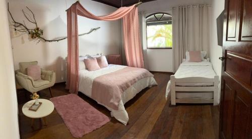 a bedroom with a canopy bed and a chair at Hospedagem Flor de Alissah in Arraial do Cabo