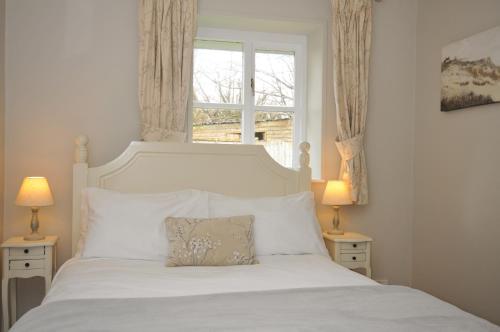 a bedroom with a white bed with a window at Stocks Barn in Liskeard