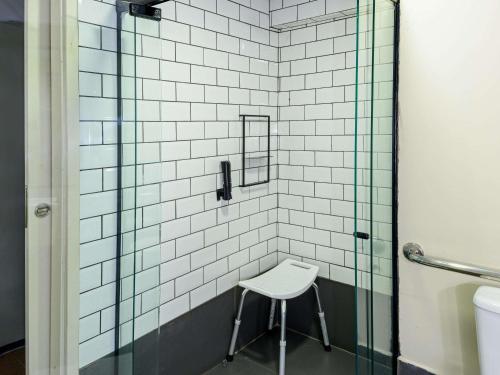 a stool in a bathroom with a glass shower at ibis Sao Luis in São Luís