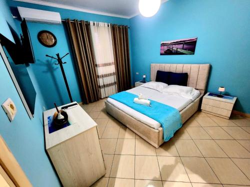 a blue bedroom with a bed and a cross on the wall at Apartament me qira ditore "AGA"Fier in Fier