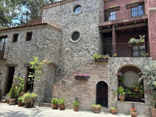 an old brick building with potted plants on it at Hermoso departamento en Val’Quirico Loft Frontana in Tlaxcala de Xicohténcatl