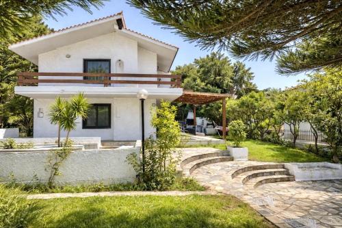 a house in the middle of a garden at Villa Naya by the Beach in Anavyssos