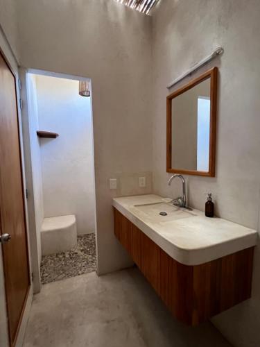 a bathroom with a sink and a mirror and a shower at Poolside Cabaña Studio with stunning ocean view in Puerto Escondido