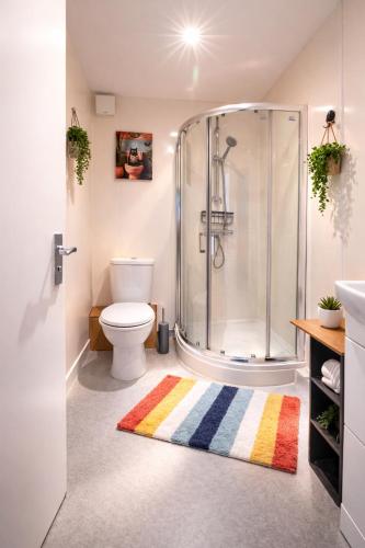 a bathroom with a shower and a toilet and a rug at Brighton Colour Pop House- Sleeps up to 12 in Brighton & Hove