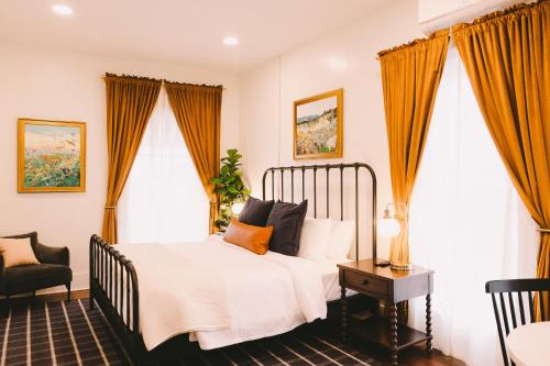 a bedroom with a bed and a chair and windows at The Historic Hattie House in Abingdon