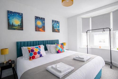 a white bedroom with a large bed with colorful pillows at Brighton Colour Pop House- Sleeps up to 12 in Brighton & Hove