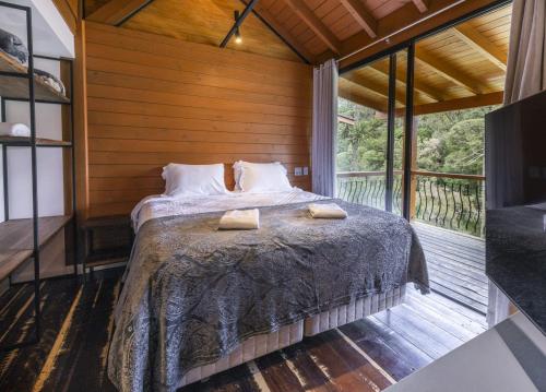 a bedroom with a bed and a large window at Pousada Amigos da Montanha in Urubici