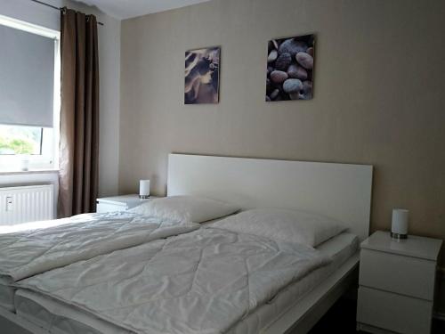 a bed in a bedroom with two pictures on the wall at Ferienwohnung Sonnenplatz in Fehmarn