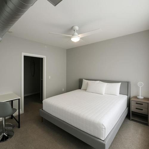 a bedroom with a white bed and a ceiling fan at Axis Suite in Des Moines