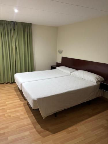 a bedroom with a large white bed with green curtains at Hostal Ripollès in Ripoll