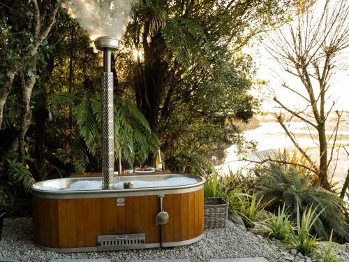 a hot tub with a fountain in a garden at Hightide River Escape -with Outdoor Bath in Hokitika