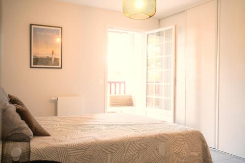 a white bedroom with a bed and a window at Grand appartement-lac-centre-hossegor in Hossegor