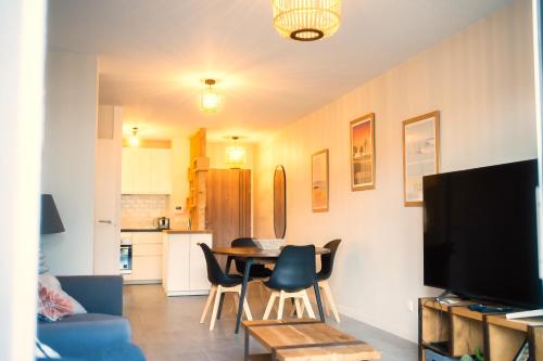 a living room with a table and chairs and a kitchen at Grand appartement-lac-centre-hossegor in Hossegor