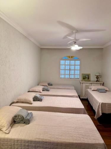 three beds in a room with a window at Casarão José Morada in Belo Horizonte