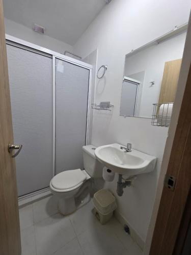 a white bathroom with a toilet and a sink at El apartacho de Andres in Valledupar