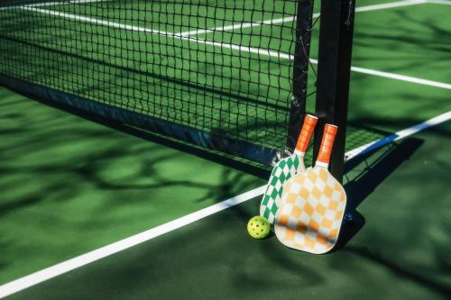 two tennis rackets and a ball on a tennis court at Petit Cowboy in New Braunfels