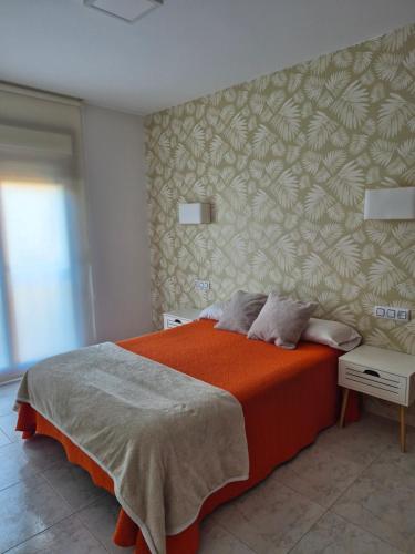 a bedroom with a bed with an orange blanket at Apartamentos Corea in Portonovo